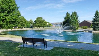 a park bench sitting in front of a water fountain